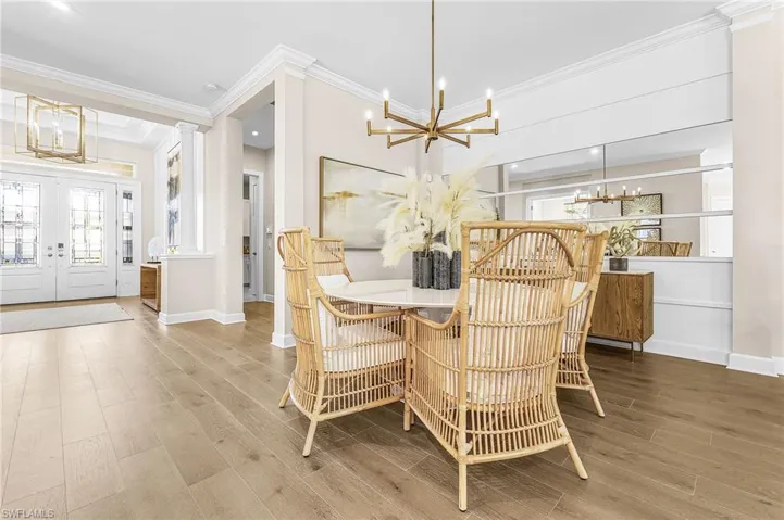 Dining area featuring suspended lighting, ornate columns, wood finished floors, crown molding, and french doors