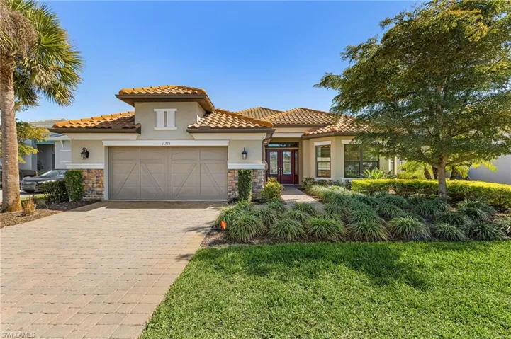 Mediterranean / spanish-style house with stone siding, french doors, stucco siding, a front yard, and decorative driveway