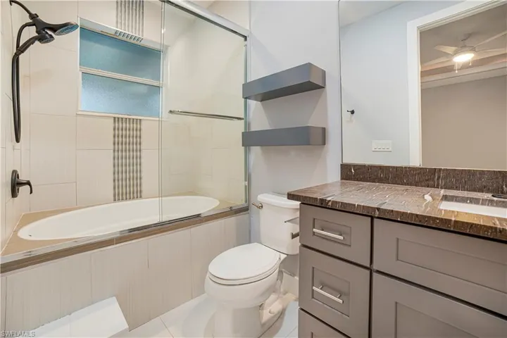 Full bathroom with vanity, toilet, tile patterned flooring, and bath / shower combo with glass door