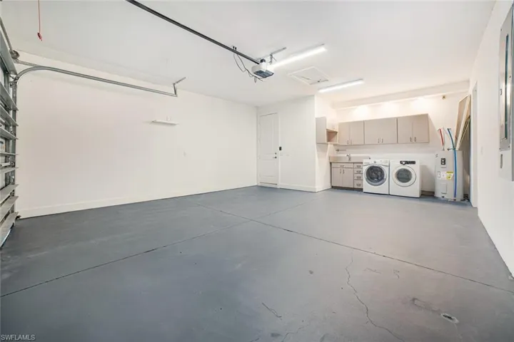 Garage featuring a garage door opener, water heater, and separate washer and dryer