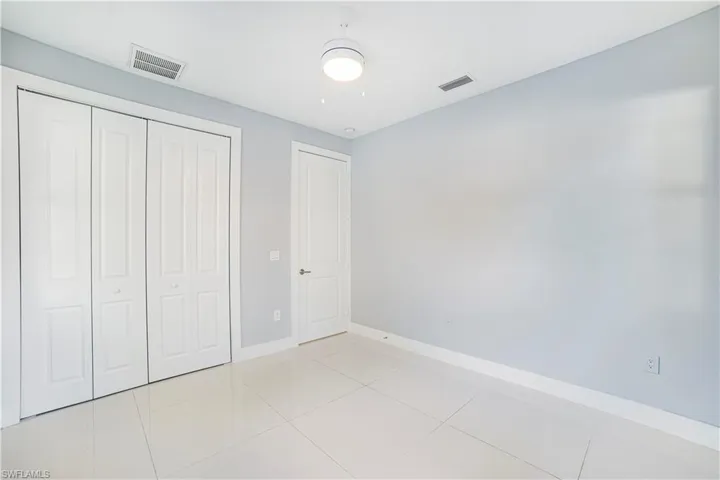 Unfurnished bedroom featuring a closet, light tile patterned floors, and ceiling fan