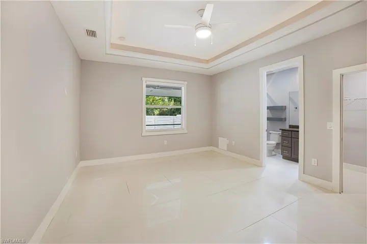 Tiled spare room with a tray ceiling and ceiling fan