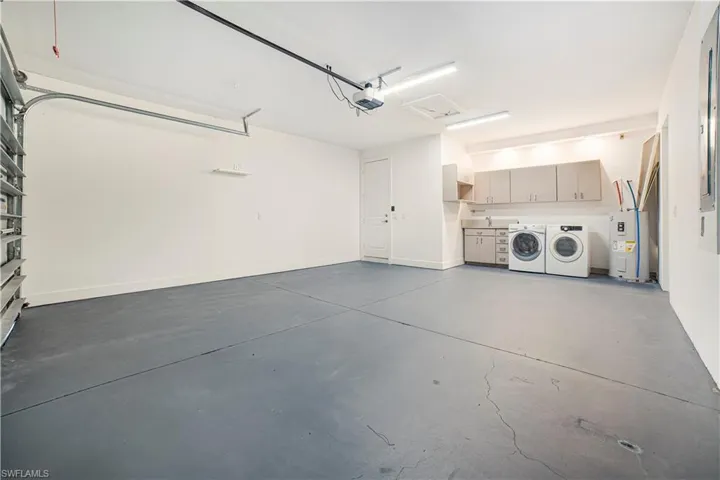 Garage featuring a garage door opener, electric water heater, and independent washer and dryer