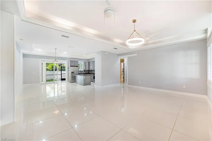 Unfurnished living room featuring light tile patterned floors and a raised ceiling