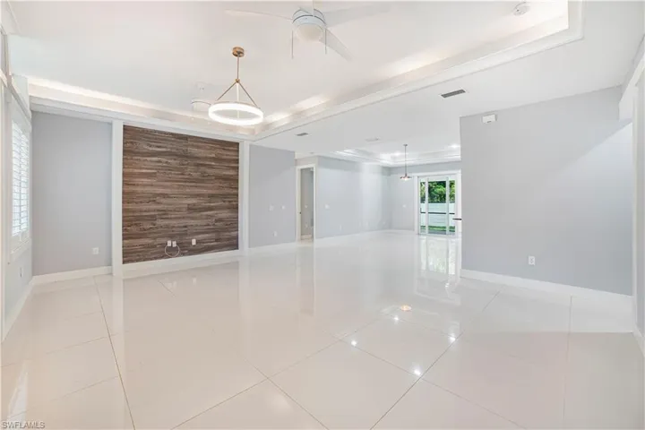 Spare room featuring ceiling fan, a tray ceiling, and light tile patterned floors