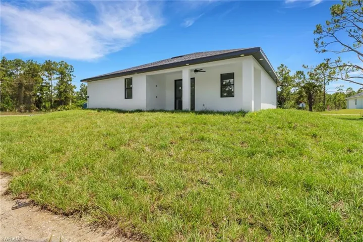 Rear view of house featuring ceiling fan and a yard