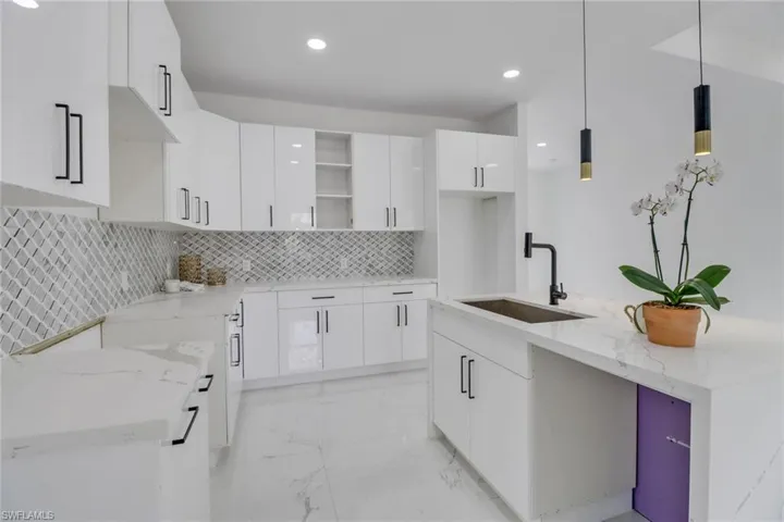 Kitchen with white cabinets, pendant lighting, and sink
