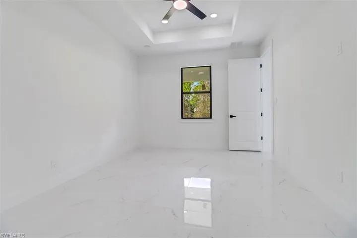 Empty room featuring ceiling fan and a tray ceiling