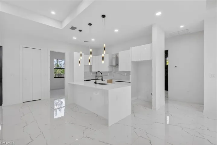 Kitchen featuring a white waterfall island, pendant lighting, white cabinetry, and a black faucet
