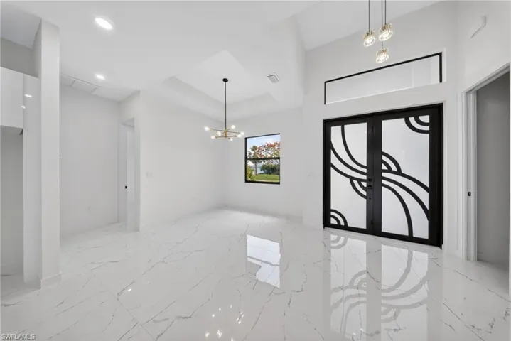 Entryway featuring double doors with decorative frosted glass, an overhead transom window, and a vaulted ceiling