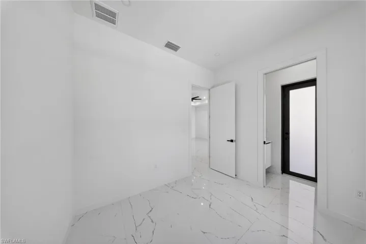 Bright room featuring white walls, white ceiling, white doors, and white marble-look flooring