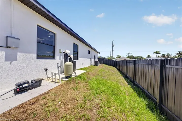 Exterior side of the property featuring a white stucco finish, dark-framed windows, and a black metal privacy fence