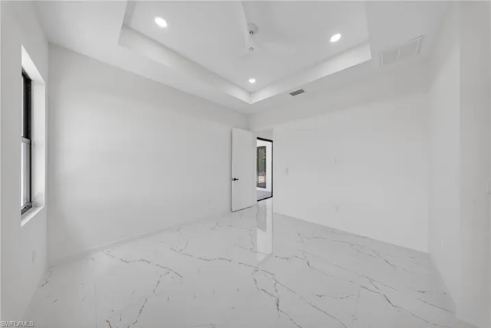 Spacious room featuring white walls and large-format porcelain tile flooring with grey veining