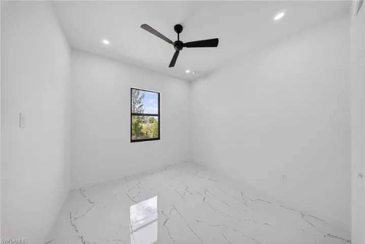 Room featuring large-format tile flooring with a marble-effect pattern, a single black-framed window, and a black ceiling fan