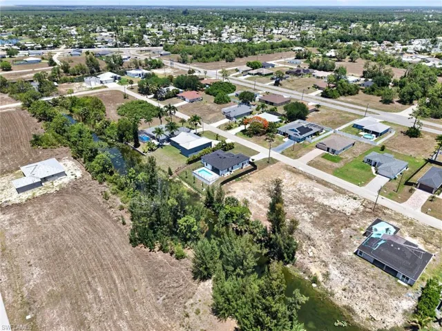 Expansive aerial view of a residential area featuring numerous single-story homes, a network of paved roads, and several properties with private swimming pools