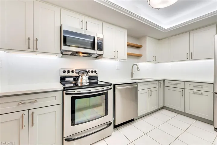 Kitchen featuring stainless steel appliances, open shelves, white cabinetry, and light tile patterned floors