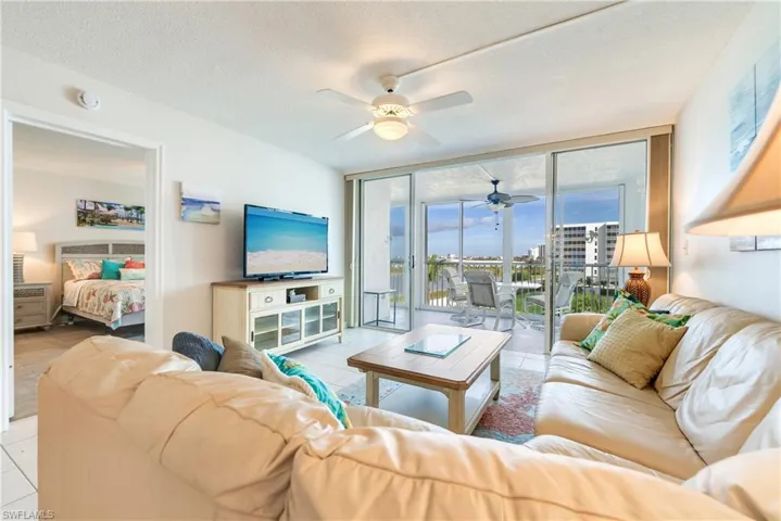Living room featuring floor to ceiling windows, a textured ceiling, a ceiling fan, and light tile patterned flooring