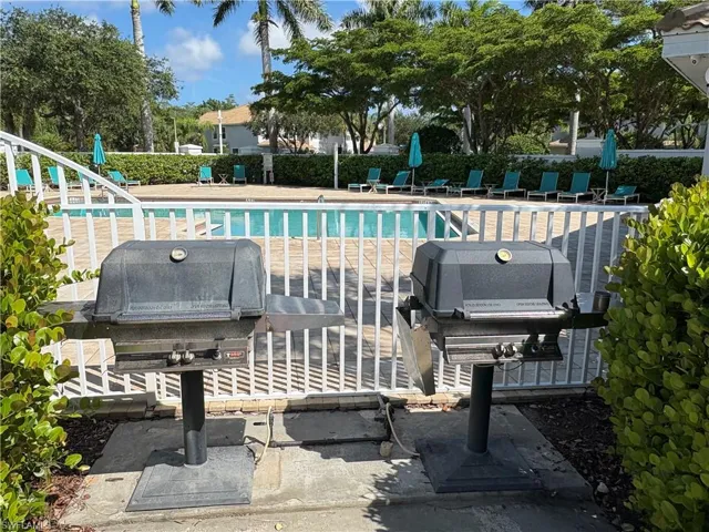 Community pool with a patio area and a grill