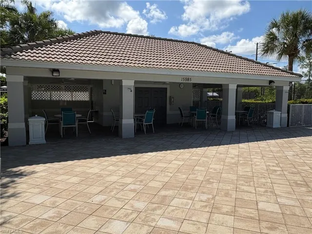 Community pool area with outdoor dining space, a tiled roof, stucco siding, and a patio