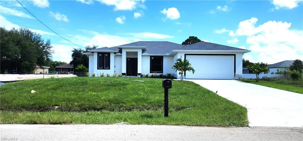 View of front of home with a garage and a front lawn