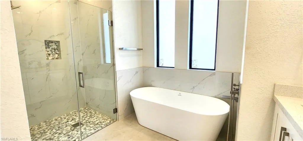 Bathroom with vanity, tile patterned flooring, and separate shower and tub