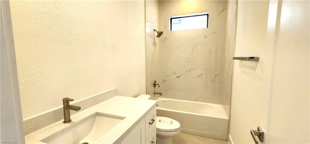 Full bathroom featuring tile patterned floors, toilet, vanity, and tiled shower / bath