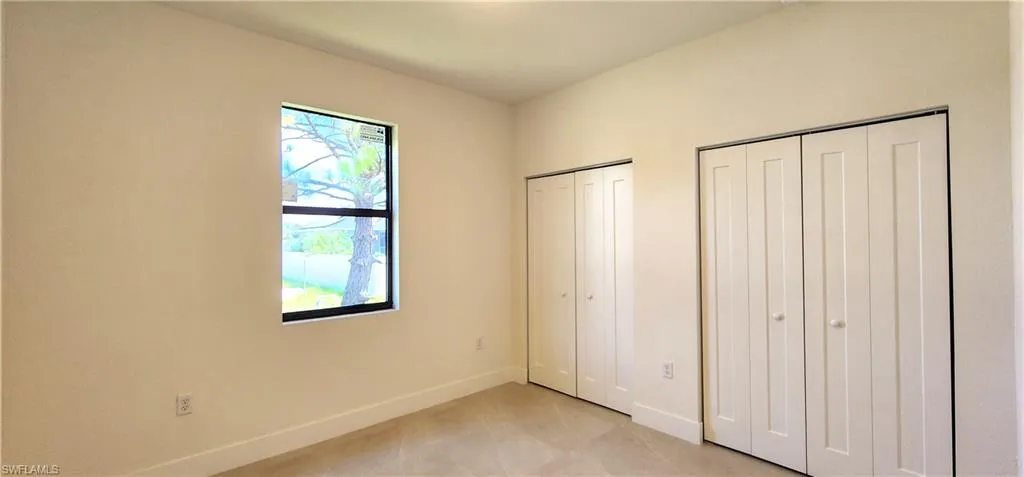 Unfurnished bedroom with two closets and multiple windows