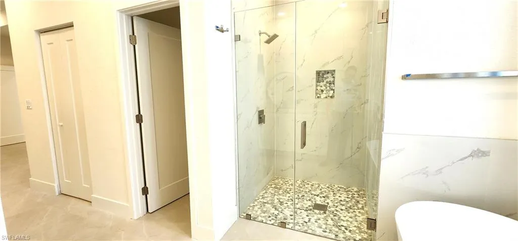 Bathroom featuring walk in shower, tile patterned floors, and toilet