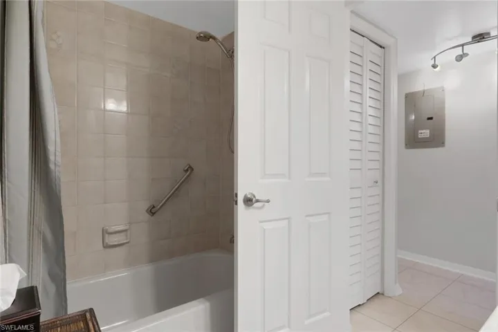 Full bathroom featuring a closet, shower / bath combo with shower curtain, electric panel, and light tile patterned flooring