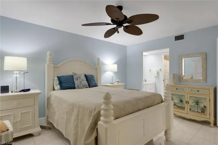 Bedroom featuring light tile patterned floors, ceiling fan, and connected bathroom