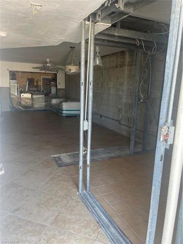 View from condo unit entry door of entry hall, kitchen, dining area, living room and lanai covered in plywood