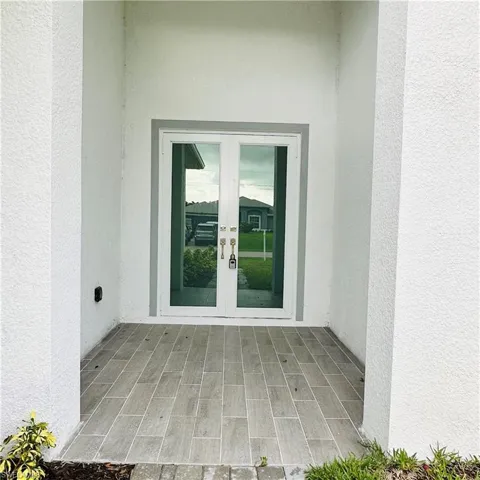 Entrance to property featuring a patio, stucco siding, and french doors