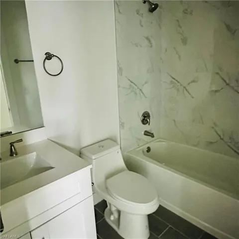 Bathroom featuring shower / bath combination, vanity, and dark tile patterned flooring