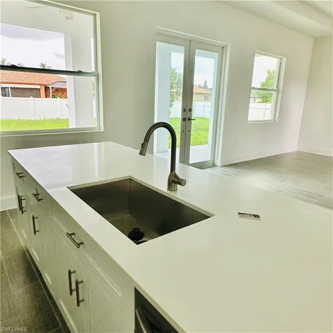 Kitchen with french doors, white cabinets, light stone counters, and dark wood-style flooring