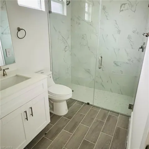 Bathroom featuring a marble finish shower, vanity, and wood tiled floors