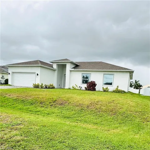 View of front of home featuring an attached garage, stucco siding, a front lawn, and driveway