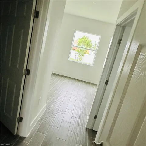 Corridor featuring baseboards and wood tiled floors