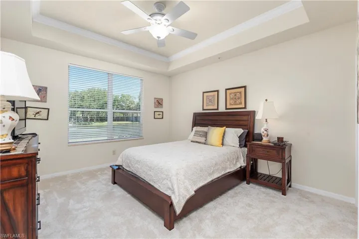 Bedroom with a raised ceiling, baseboards, crown molding, and light colored carpet
