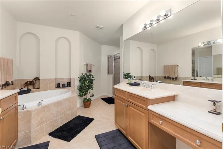 Full bath featuring a shower stall, tile patterned floors, visible vents, vanity, and a garden tub