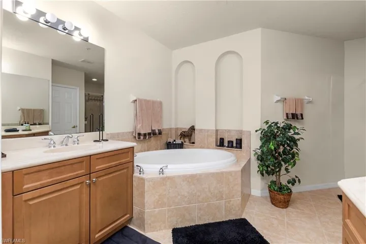 Full bathroom featuring a bath, an enclosed shower, vanity, and tile patterned floors