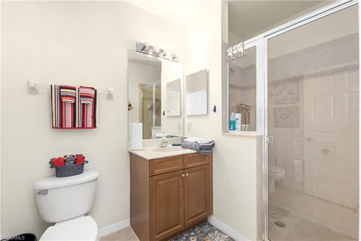 Full bathroom featuring baseboards, a shower stall, toilet, and vanity