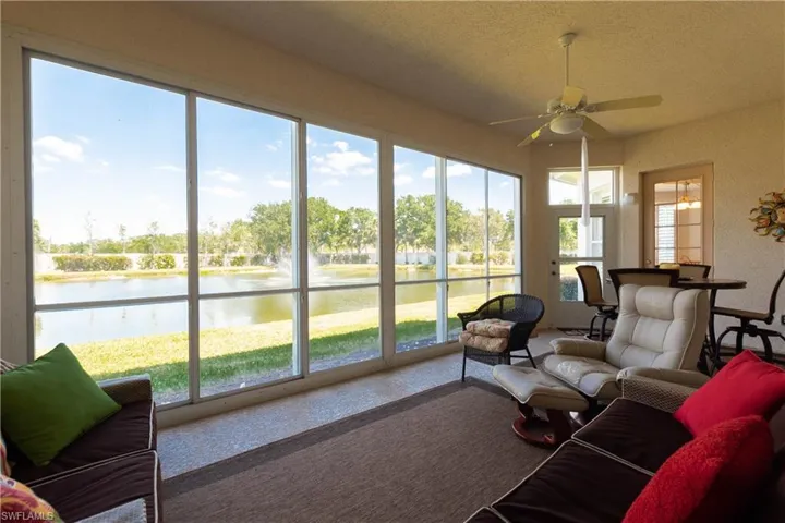 Sunroom / solarium with ceiling fan, a textured ceiling, a water view, and carpet