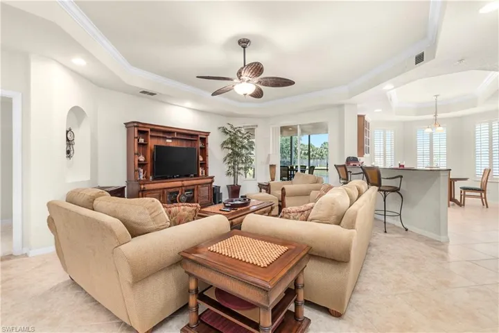 Living area featuring a tray ceiling, visible vents, crown molding, and light tile patterned floors