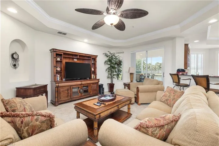 Living room with recessed lighting, a tray ceiling, visible vents, a ceiling fan, and ornamental molding
