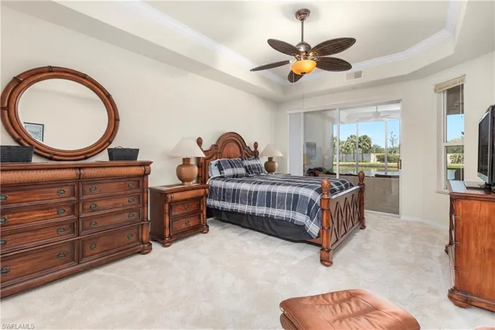Bedroom featuring a raised ceiling, visible vents, ornamental molding, light carpet, and access to outside