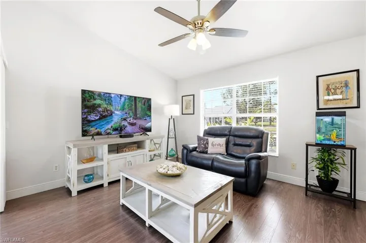 Living area with dark wood-type flooring, vaulted ceiling, and a ceiling fan