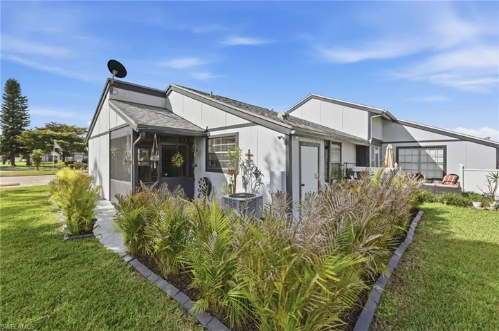 Back of house with a lawn, a sunroom, and a shingled roof