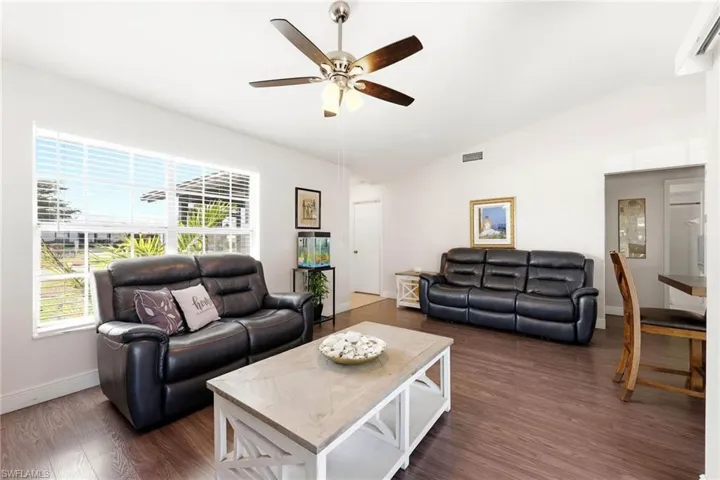 Living area with vaulted ceiling, dark wood-type flooring, and a ceiling fan