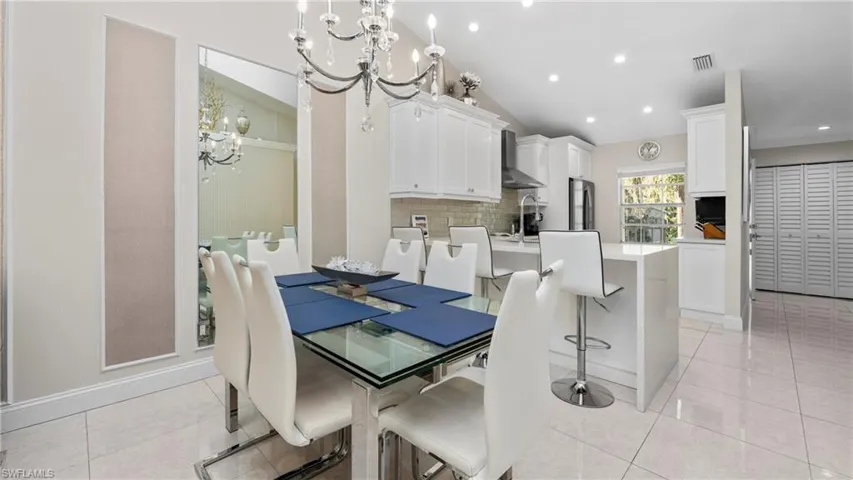 Dining area with a chandelier, vaulted ceiling, light tile patterned floors, and recessed lighting