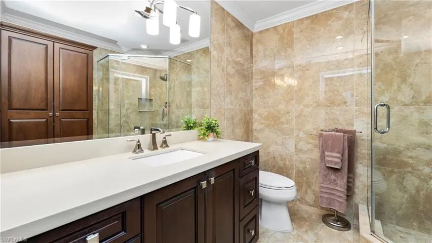 Bathroom with ornamental molding, tile walls, a shower stall, and vanity